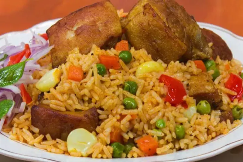 Plato de arroz con chancho servido con presas de cerdo doradas y salsa criolla