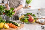 Verduras y frutas frescas siendo lavadas en un bowl con agua y vinagre sobre una mesa de cocina